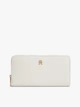 Billetera de poliuretano color blanco con textura y monograma TH en bajo relieve, cierre de cremallera e insignia metálica dorada en el frente.