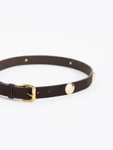 Cinturón de cuero descarne color suela, con hebilla metálica dorada y apliques circulares decorativos distribuidos a lo largo de la pieza.