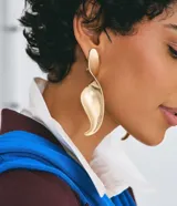 Par de caravanas grandes de diseño escultural con efecto torcido, confeccionadas en metal con acabado dorado.