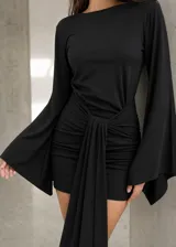 Vestido corto negro con espalda descubierta, mangas largas acampanadas y corte ajustado.