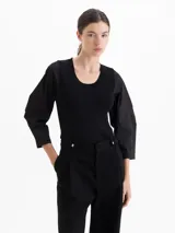 Top de tejido de punto acanalado con cuello redondo y mangas de tela plana con volumen. Presenta una silueta ajustada al cuerpo y mangas tres cuartos.