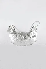 Bolso de hombro tipo banana, confeccionado en cuero metalizado plateado. Tiene cierre superior, forro interior con bolsillo y asa corta de cuero con costuras visibles. Incluye una correa de cadena desmontable.