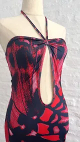 Vestido corto con estampado abstracto en tonos rojo y negro, escote halter con abertura en el pecho y corte ajustado al cuerpo.