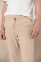 Pantalón de ramio y algodón color beige, con cintura elástica ajustable con cordón y ruedo con dobladillo.