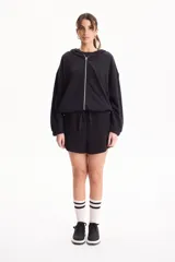 Campera deportiva negra de corte bomber sin friza, con cierre frontal completo, capucha y elásticos ajustables en la cintura.