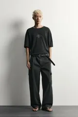 Camiseta de corte relaxed fit color negro, confeccionada en tejido ligero con mezcla de algodón y lino, con cuello redondo, manga corta y efecto lavado. Presenta estampado de texto en el frente.