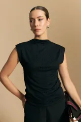 Top sin mangas de tejido texturizado con brillo integrado, color beige dorado, con cuello alto y hombros levemente estructurados.