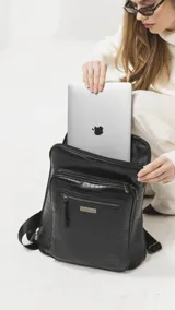 Mochila de diseño rectangular con textura símil cuero efecto cocodrilo en color tostado. Cuenta con un bolsillo frontal con cierre, compartimento principal con doble cierre, correas ajustables y manija superior. Incluye detalles metálicos y placa con logo de la marca.