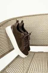 Zapatillas urbanas de cuero, color marrón oscuro, con paneles de gamuza y cuero liso, cordones al tono y suela de plataforma blanca.
