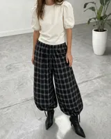 Pantalón de corte amplio y holgado con diseño a cuadros, cintura elástica con cordón ajustable y bajos regulables en las piernas.