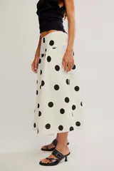 Falda midi de corte A y cintura baja, confeccionada en popelina de algodón color marrón terracota con estampado de lunares celestes.