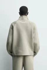 Sudadera de corte relajado confeccionada en tejido técnico interlock de algodón con elasticidad. Presenta cuello subido, cierre frontal con cremallera, manga larga con puños acanalados y bolsillos laterales ocultos en las costuras.