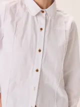 Camisa de corte femenino y sofisticado, con cuello redondo, manga larga y cierre frontal de botones. Confeccionada 100% en algodón.