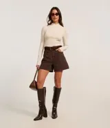 Short de sarga color blanco, corte mom, tiro alto, con trabillas en la cintura y bolsillos. Tiene cierre tradicional por botón y cremallera.