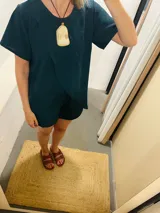 Conjunto de dos piezas color celeste claro, compuesto por un remerón de manga corta con diseño cruzado envolvente en la parte delantera y un short liso a juego.