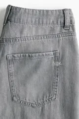 Jean de corte wide leg y tiro medio en denim color gris deslavado, con diseño de cinco bolsillos y cierre frontal con botón y cremallera.
