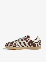 Championes Adidas Samba OG con diseño de estampado animal print de vaca en tonos marrón y blanco. Presenta las icónicas tres bandas laterales en blanco, cordones en color celeste y suela de goma natural.