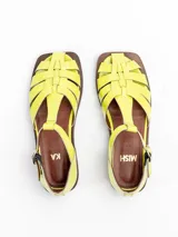 Sandalias tipo guillermina Bliss de cuero charol color amarillo, con capellada entretejida, tira en T y cierre de hebilla lateral. Posee suela plana y taco bajo.