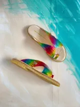 Sandalias de cuero vacuno modelo Anika de Carolina De Cunto, con diseño metalizado de efecto tornasolado en tonos arcoiris, tiras cruzadas y presilla para el dedo. Poseen suela plana y taco bajo de 2 cm.