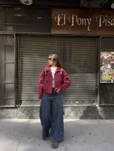 Campera tipo bomber color bordó, confeccionada en gamuza, con cierre frontal y bordados decorativos en el pecho y las mangas. Presenta un diseño holgado con puños y cuello clásico.