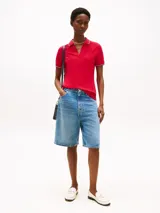 Chomba deportiva de algodón elástico color rojo, con corte slim, escote de pico y ribetes distintivos en blanco y azul marino en el cuello y los puños. Presenta el logo de Tommy Hilfiger bordado en el pecho.