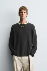 Jersey de manga larga, cuello redondo y calce relajado, color negro con efecto lavado y textura tejida.