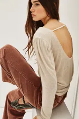 Remera de viscosa en color beige, de manga larga con detalle de frunces en los hombros y un pronunciado escote en la espalda con tira horizontal.