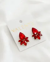 Par de aros colgantes con forma de flor, con piedras rojas y strass engarzados en metal dorado.