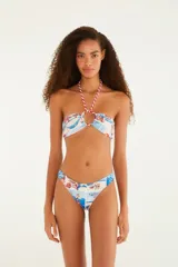 Conjunto de bikini estampado con motivos playeros en tonos celeste, blanco y rojo. El corpiño es bandeau con aro y tirante halter con detalle de argolla. La bombacha es de corte clásico.