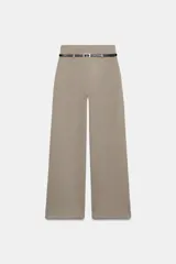 Pantalón palazzo de tiro alto color beige, con pierna ancha y cinturón fino de efecto piel negro con hebilla metálica.