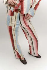 Pantalón de gabardina de tiro medio con diseño de rayas verticales en tonos rosado, rojo, celeste, beige y negro. Cuenta con bolsillos frontales aplicados y cierre con botón.