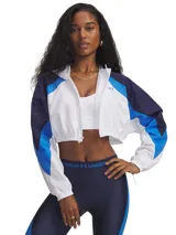 Campera deportiva de corte cropped con diseño color block en blanco, azul marino y azul eléctrico. Confeccionada en tejido ligero de nailon con textura arrugada, cuenta con cierre frontal, cuello alto y puños elásticos.