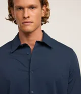 Camisa masculina de manga larga, cuello inglés y cierre frontal de botones, confeccionada en poliamida con elastano y tecnología performance.