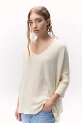 Sweater de tejido de punto color crema, con escote en V y calce holgado. Presenta mangas tres cuartos con puños acanalados anchos.