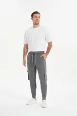 Babucha de estilo cargo en color gris, con cintura elástica ajustable mediante cordón, bolsillos laterales con solapa y puños elásticos en los tobillos.
