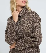 Camisa de corte oversized confeccionada en denim de algodón, con estampado animal print. Presenta cuello camisero, cierre frontal abotonado, manga larga y bolsillo en el pecho.