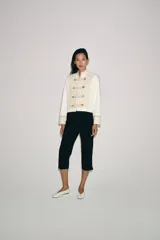 Chaqueta de estilo militar de ZARA Woman Collection, confeccionada en mezcla de algodón en color blanco y beige. Presenta cuello subido, manga larga con puños anchos en contraste y cierre frontal con alamares y botones metálicos en relieve. Tiene bajo asimétrico con abertura en la espalda.