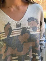 Sweater de punto con escote en V y mangas largas, de diseño holgado. Presenta un estampado animal print abstracto en tonos chocolate y detalles metalizados en color dorado sobre una base color crema.
