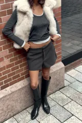 Chaleco de cuello subido y manga sisa, color beige, con efecto pelo. Incluye bolsillos laterales ocultos en la costura, forro interior combinado y cierre frontal con ganchos metálicos forrados.