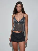 Minifalda negra de talle bajo con tira superior decorada con ojalillos metálicos.