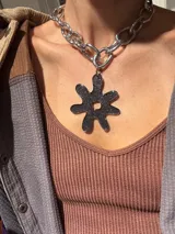 Collar plateado con cadena de eslabones grandes y dije abstracto con forma de flor color negro con glitter. El dije es desmontable.