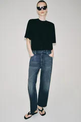 Jeans de tiro bajo con corte loose leg y largo tobillero. Presenta diseño de cinco bolsillos, cierre frontal con cremallera y botón, y acabado con efecto lavado.