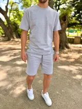 Conjunto deportivo gris melange compuesto por remera de manga corta y short con cordón ajustable en la cintura.