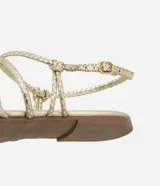 Sandalia plana dorada con punta de hoja y tiras finas con textura de serpiente. Ajuste con hebilla en el tobillo.