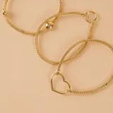 Pulsera de malla metálica con dije central en forma de corazón, ambos en acabado dorado.