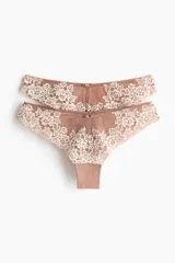 Pack de dos bombachas tipo brazilian de encaje color nude, con diseño floral y lazo decorativo en la parte delantera.