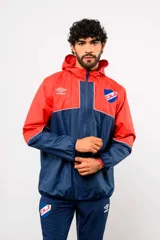 Campera de lluvia Umbro del Club Nacional de Football, modelo Drift, impermeable con capucha. Diseño bicolor en rojo y azul marino con detalles blancos, cierre frontal y bolsillos.