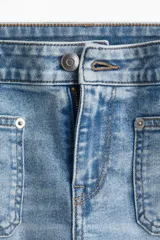 Jean de corte acampanado y largo tobillero, confeccionado en denim de lavado claro. Presenta cintura clásica con cierre y botón, bolsillos tipo parche en la parte frontal y diseño ajustado desde la cintura hasta la rodilla.
