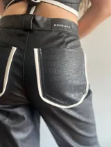 Pantalón de cuero negro con textura de piel de cocodrilo y rayas blancas laterales.