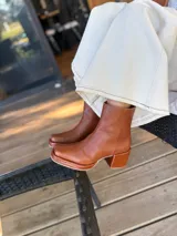 Bota de caña media color óxido, confeccionada en cuero, con plataforma y taco cuadrado texturizado, punta cuadrada y cierre lateral.